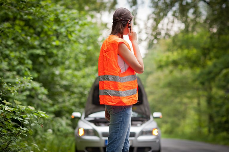 Femme portant un gilet orange fluo au bord de la route