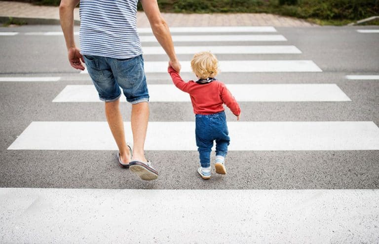 Homme qui traverse un passage piéton avec son enfant