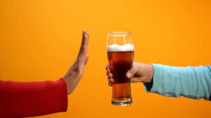 Une main fait un signe de refus face à la biere qui lui est tendue face a elle durant le dry january