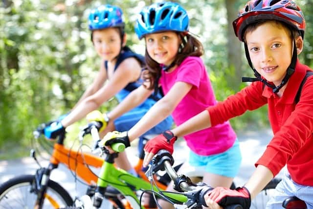 Trois enfant qui apprennent à faire du vélo